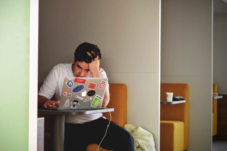 Young while male looking frustrated at his laptop.