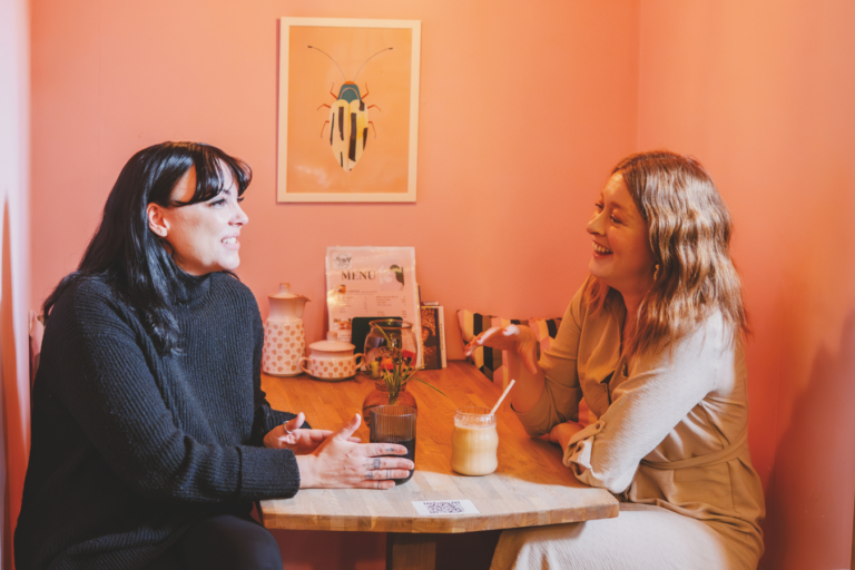 two people sat chatting which having a drink in a local cafe
